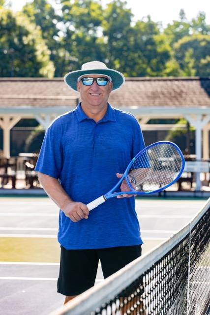 Mark Billson standing at the net of a tennis court, holding a racquet